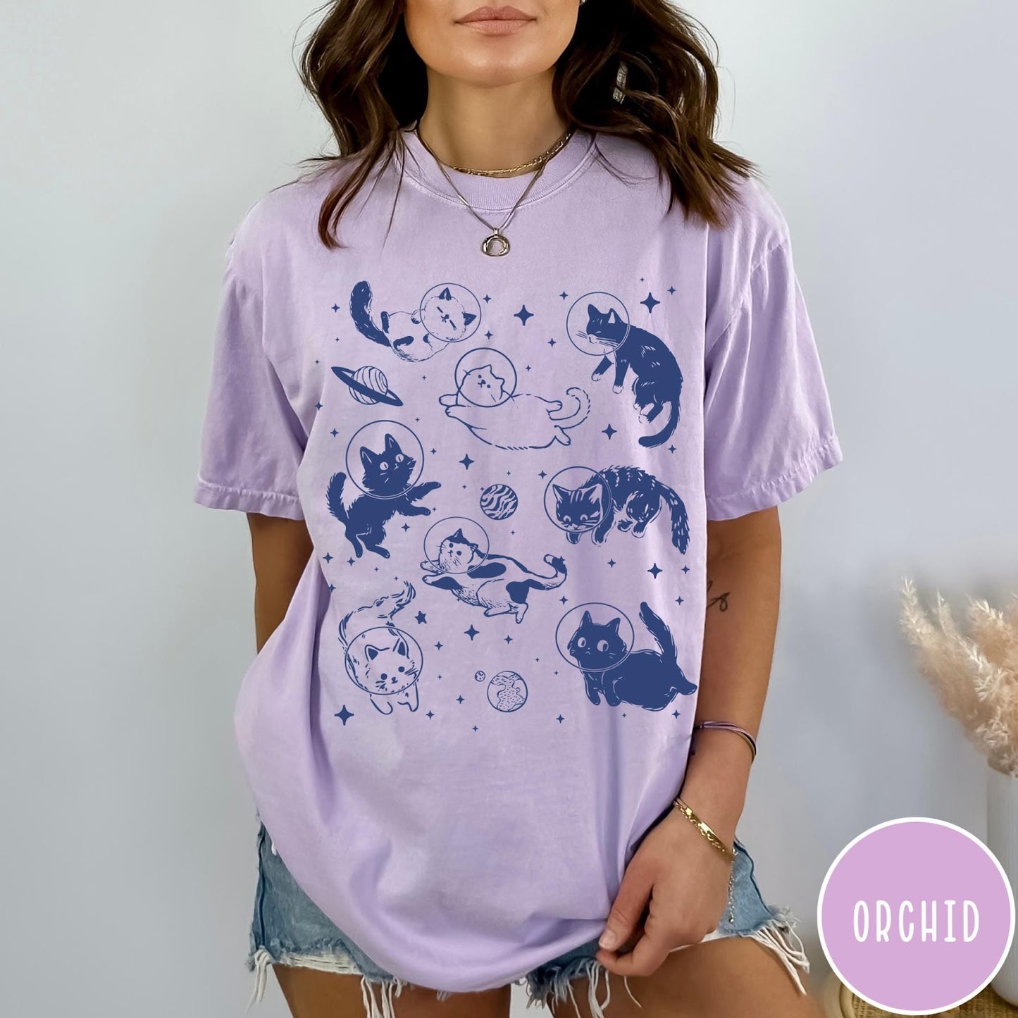 Comfort Colors tee in Orchid featuring whimsical space style graphic with multiple cats floating in space helmets