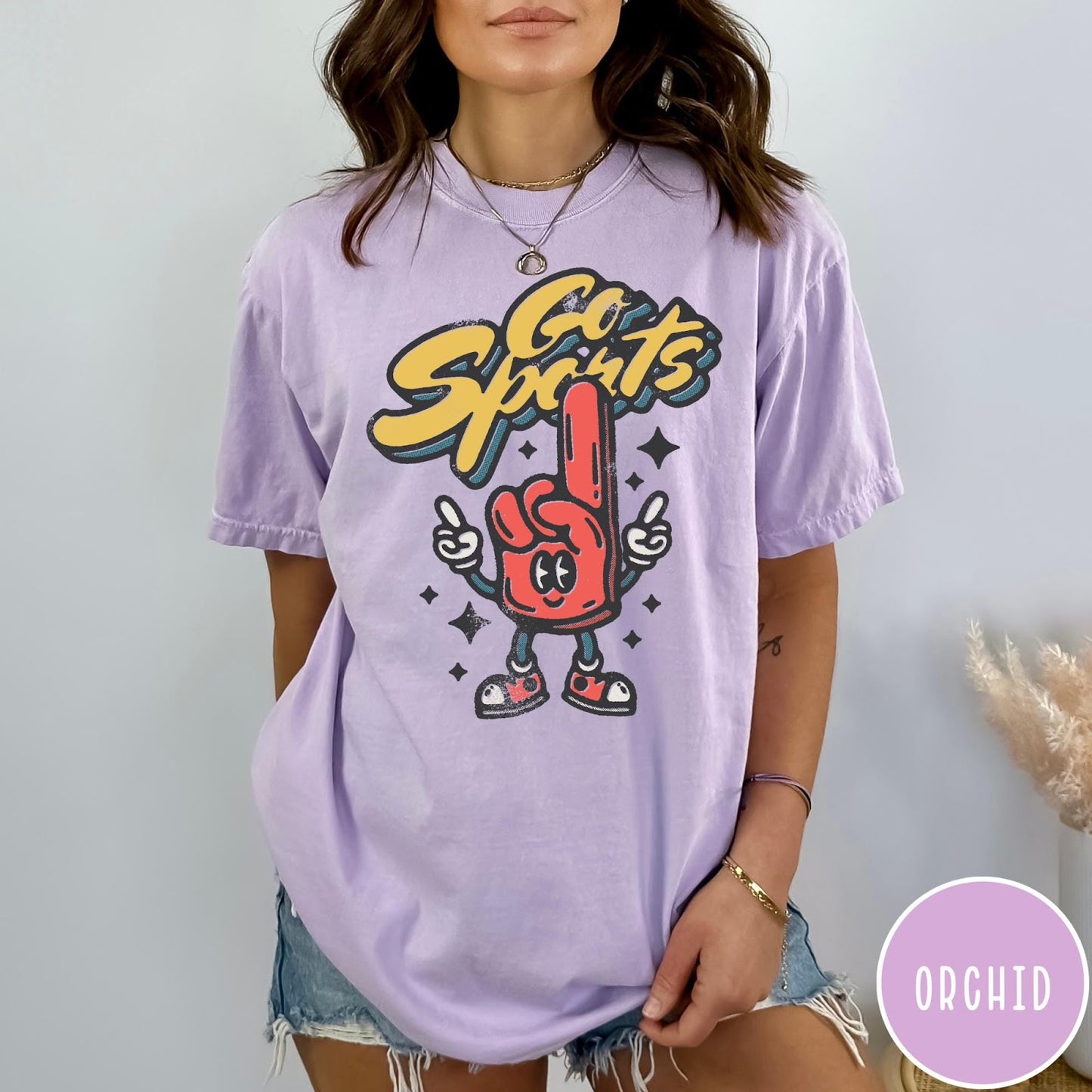 Comfort Colors tee in Orchid featuring retro mascot design with a red foam finger and Go Sports text