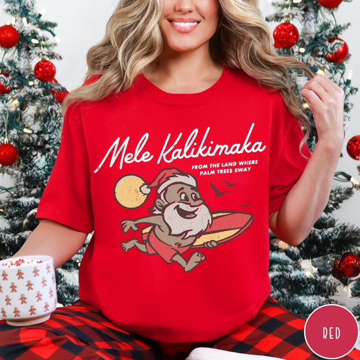 Comfort Colors tee in Red featuring vintage style graphic of a surfing Santa Claus on vacation