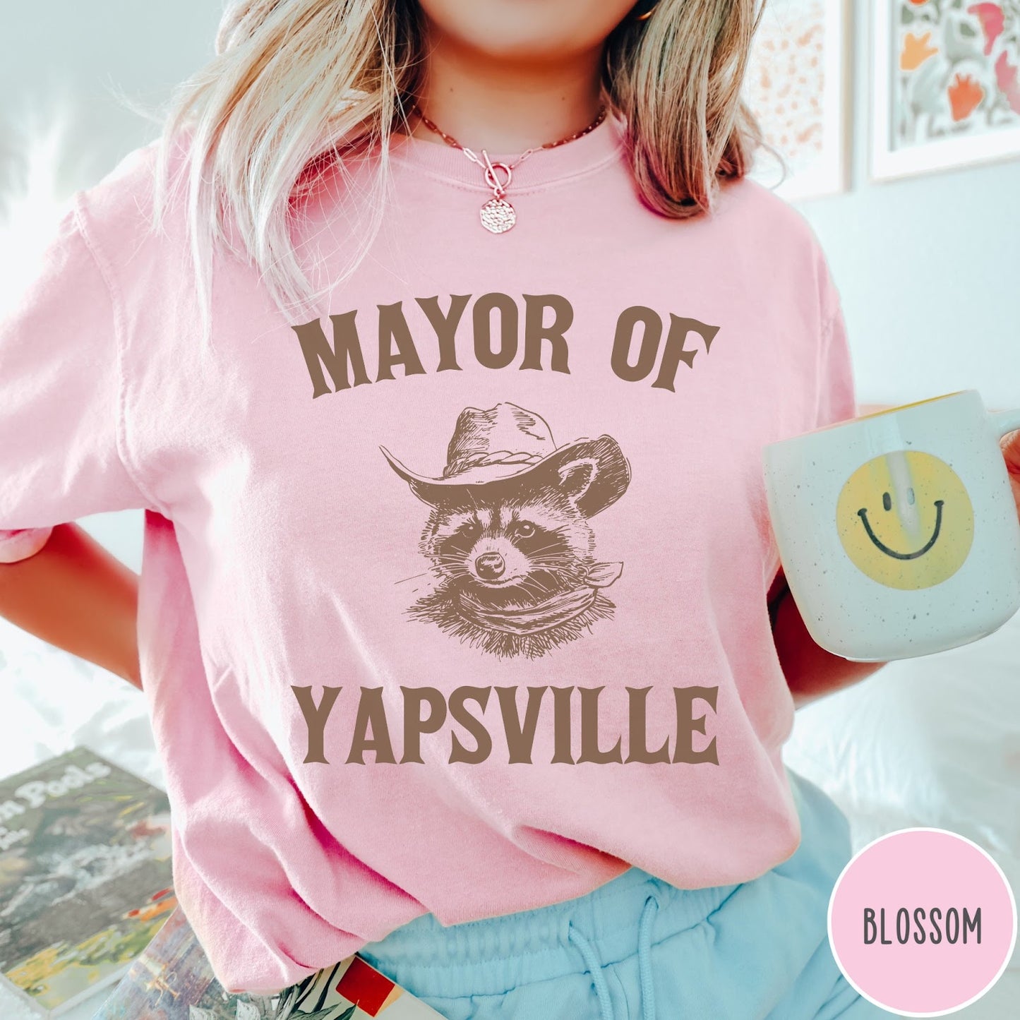Comfort Colors tee in Blossom featuring western style graphic of a raccoon wearing a cowboy hat and bandana