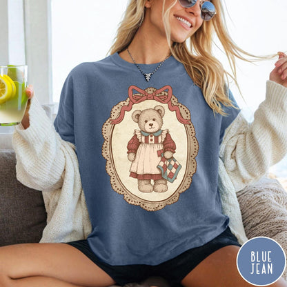 Comfort Colors tee in Blue Jean featuring vintage style teddy bear graphic inside a decorative lace oval frame