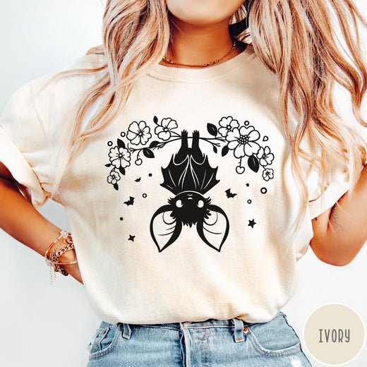 Comfort Colors tee in Ivory featuring line art style upside down bat graphic with surrounding floral elements