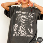 Comfort Colors tee in Pepper featuring skeleton design with sunglasses and iced coffee with laughing text graphic