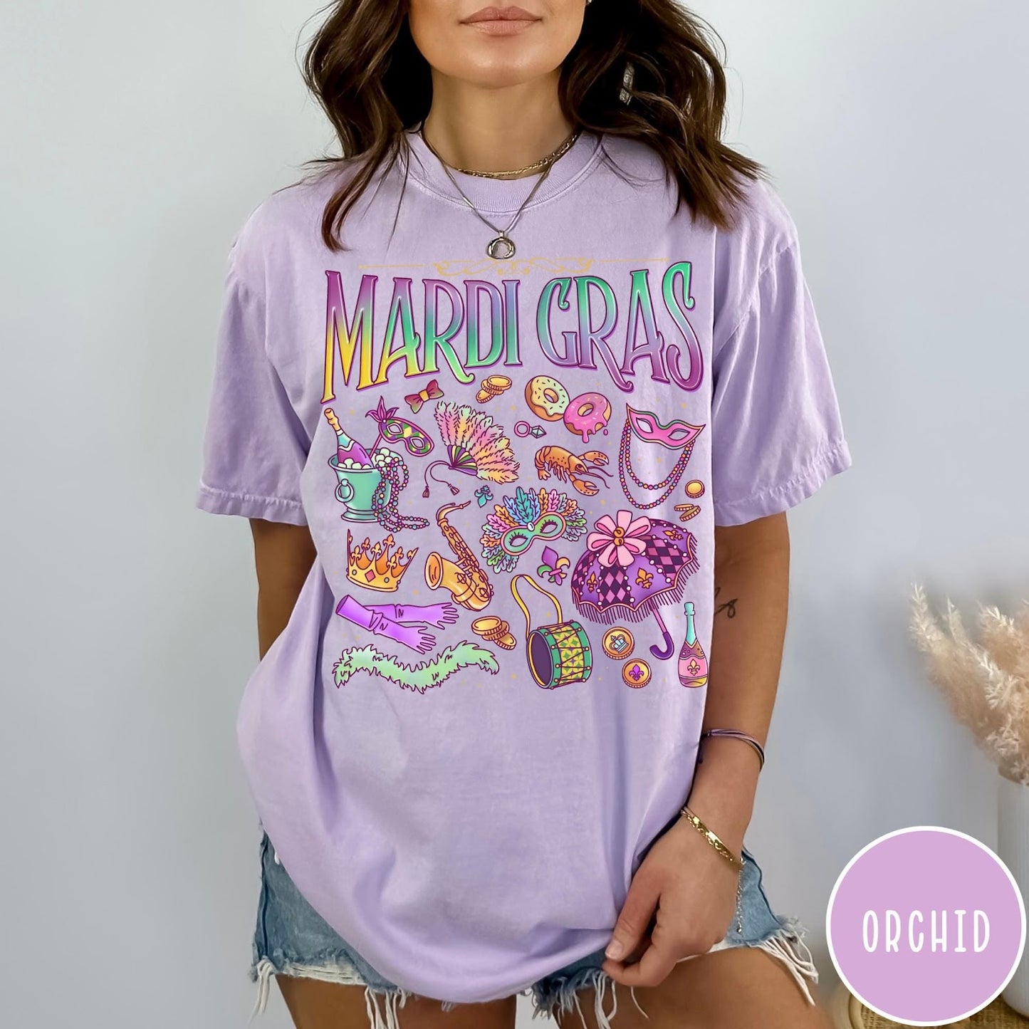 Comfort Colors tee in Orchid featuring vintage style Mardi Gras icons including a saxophone, mask, and umbrella.