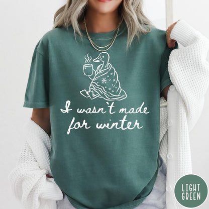 Comfort Colors tee in Light Green featuring line art graphic of a duck wrapped in a blanket drinking coffee