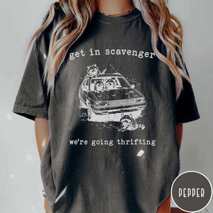 Comfort Colors tee in Pepper featuring illustrated style graphic of raccoons riding in a car and thrifting