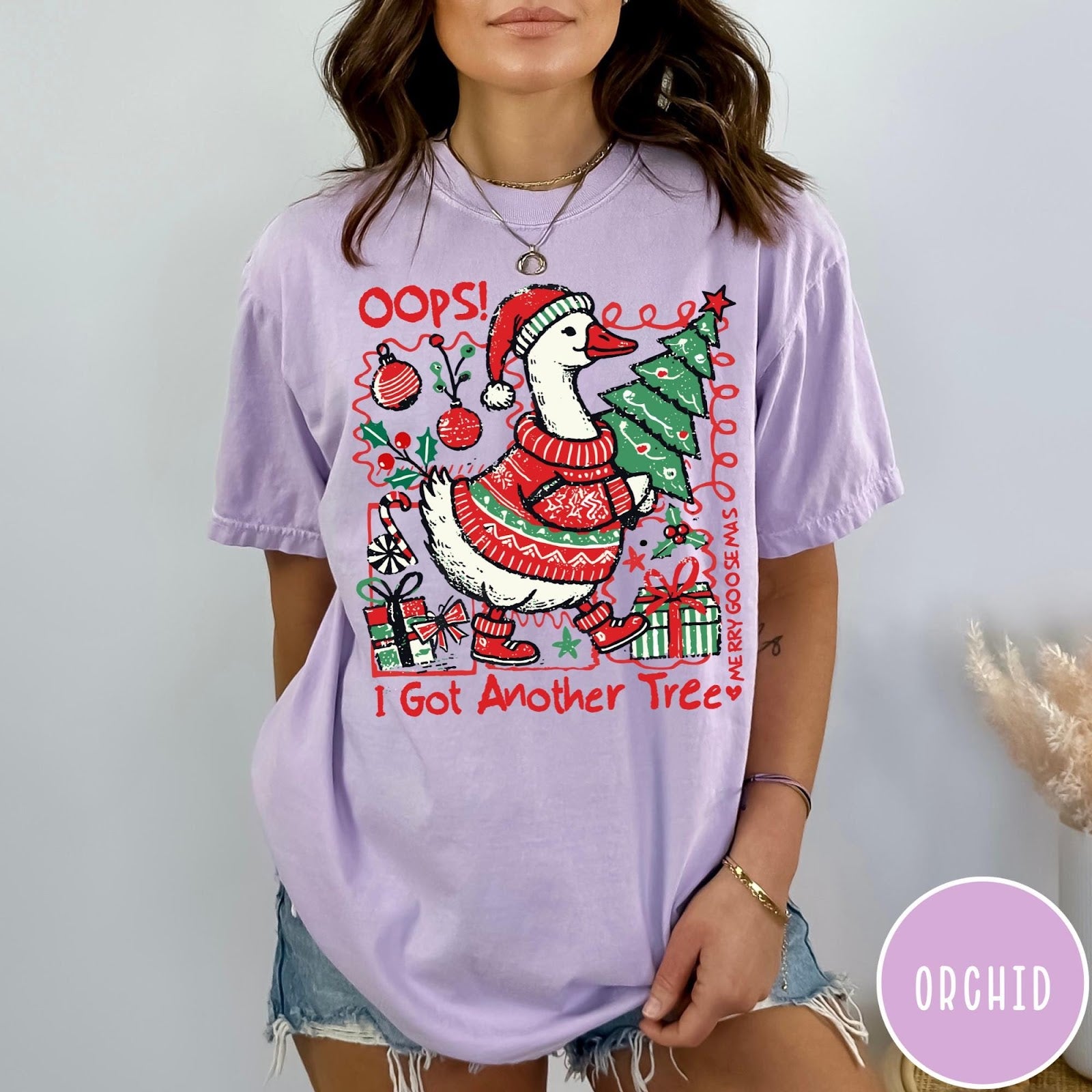 Comfort Colors tee in Orchid featuring festive goose graphic wearing a Santa hat and Christmas sweater holding tree