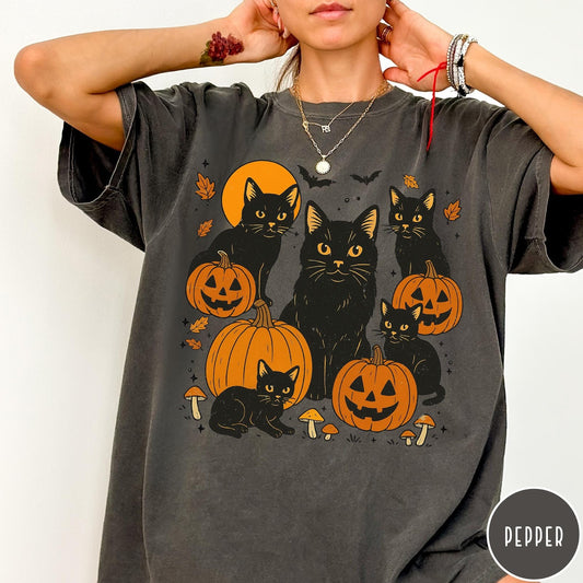 Comfort Colors tee in Pepper featuring Halloween style graphic with black cats, pumpkins, bats, and fall leaves