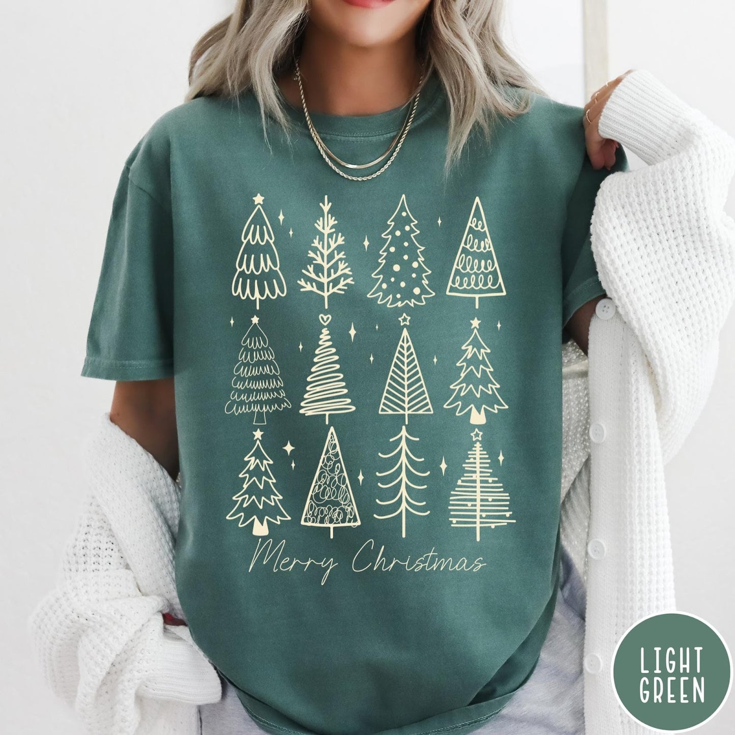 Comfort Colors tee in Light Green featuring festive graphic style with twelve unique illustrated Christmas tree designs