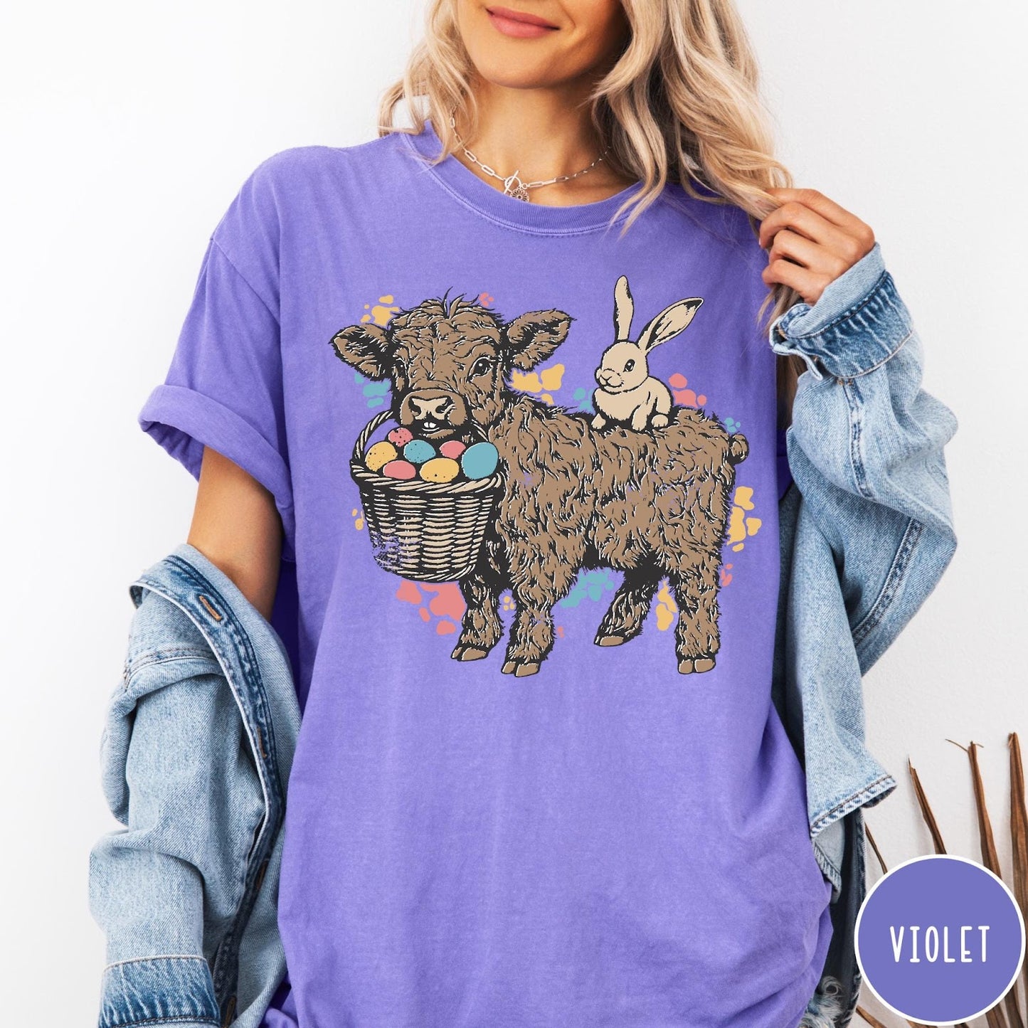 Comfort Colors tee in Violet featuring graphic style illustration of a Highland cow with bunny and eggs