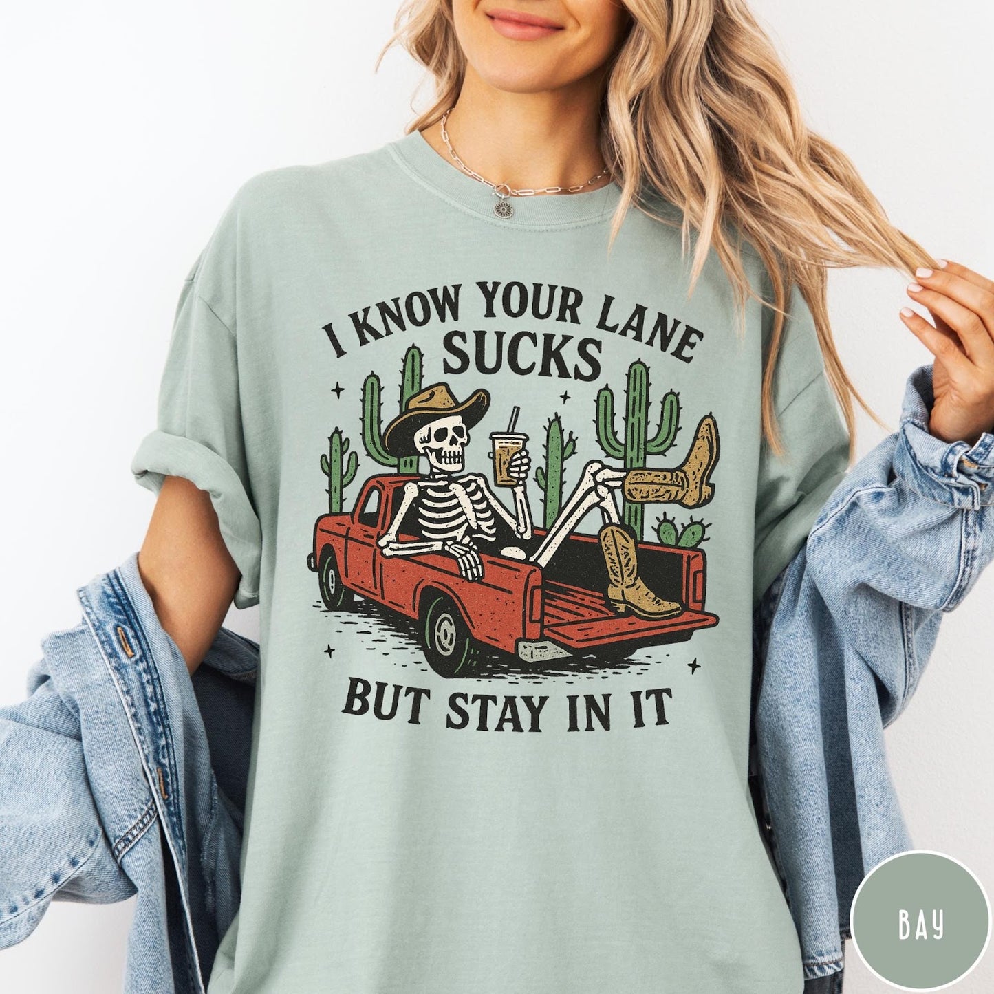 Comfort Colors tee in Bay featuring western skeleton graphic with cowboy hat and boots in pickup truck