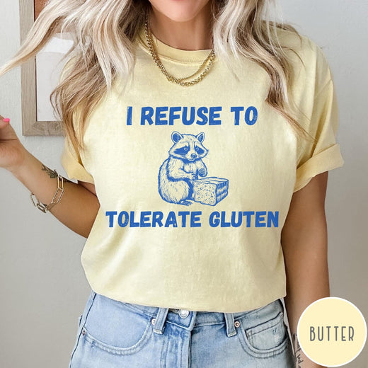 Comfort Colors tee in Butter featuring graphic style illustration of a raccoon holding a loaf of bread