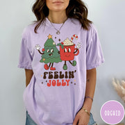 Comfort Colors tee in Orchid featuring retro style graphic of a cartoon Christmas tree and cocoa mug