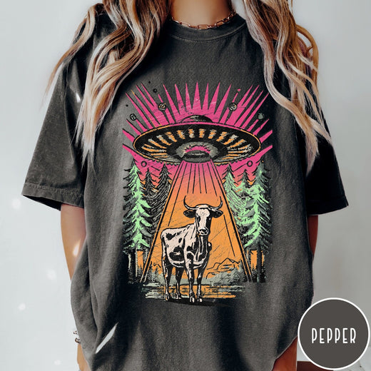 Comfort Colors tee in Pepper featuring graphic style cow being abducted by a UFO in the forest