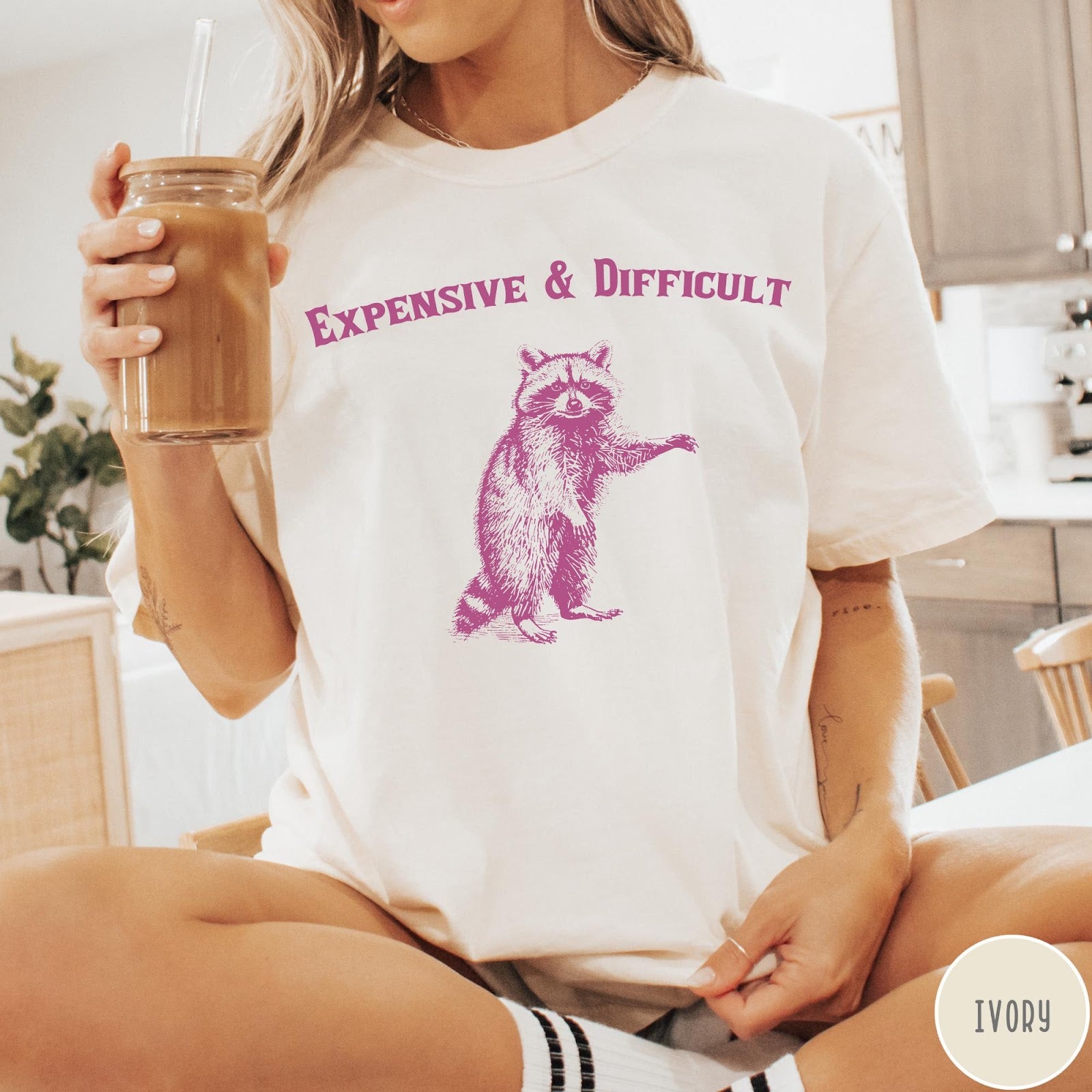 Comfort Colors tee in Ivory featuring vintage style graphic of a standing raccoon with text Expensive and Difficult