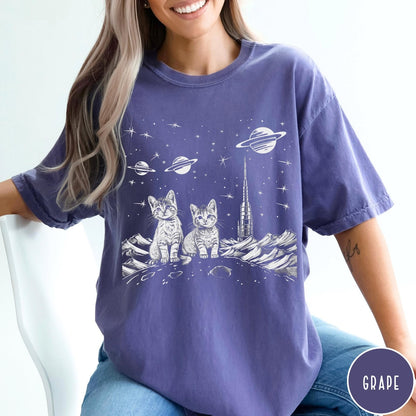 Comfort Colors tee in Grape featuring line art graphic of two kittens sitting on a planet with rocket