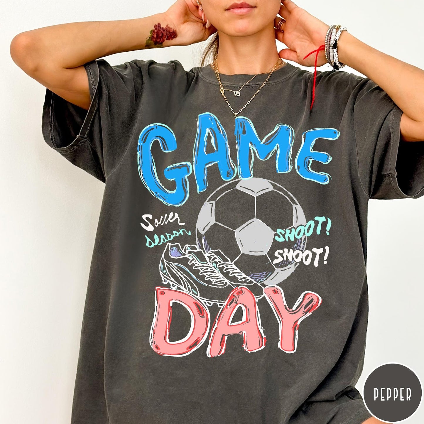 Comfort Colors tee in Pepper featuring soccer graphic with a ball, cleats, and Game Day text