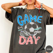 Comfort Colors tee in Pepper featuring soccer graphic with a ball, cleats, and Game Day text