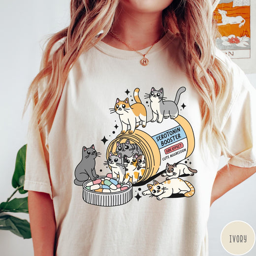 Comfort Colors tee in Ivory featuring graphic illustration of cats spilling out of a serotonin booster bottle