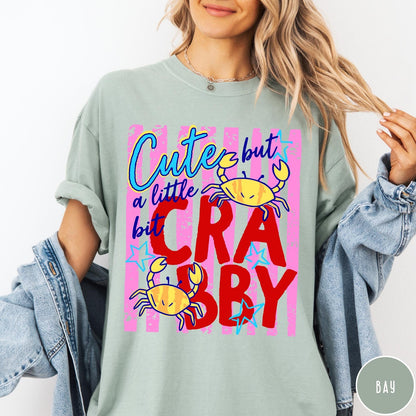 Comfort Colors tee in Bay featuring playful graphic text and yellow crab illustrations with pink stripes