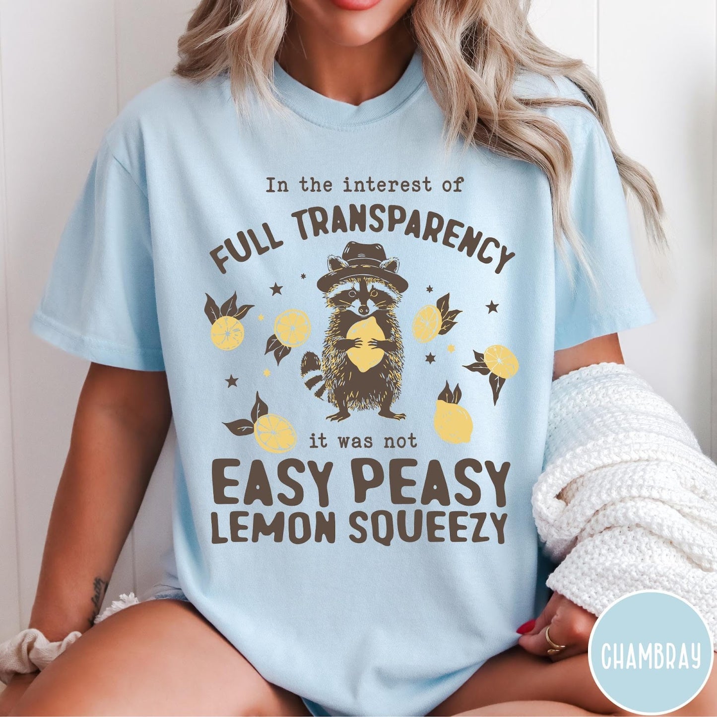 Comfort Colors tee in Chambray featuring graphic illustration of a raccoon wearing a hat holding a lemon