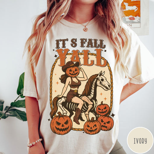 Comfort Colors tee in Ivory featuring western graphic of a pumpkin cowgirl riding a skeleton horse with pumpkins