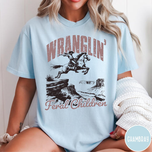 Comfort Colors tee in Chambray featuring western style graphic of a cowboy on horseback jumping a canyon