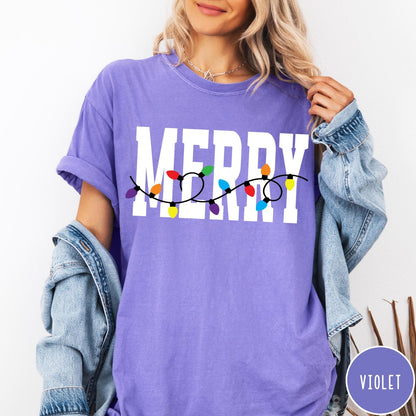 Comfort Colors tee in Violet featuring festive holiday style graphic with Merry text and Christmas lights
