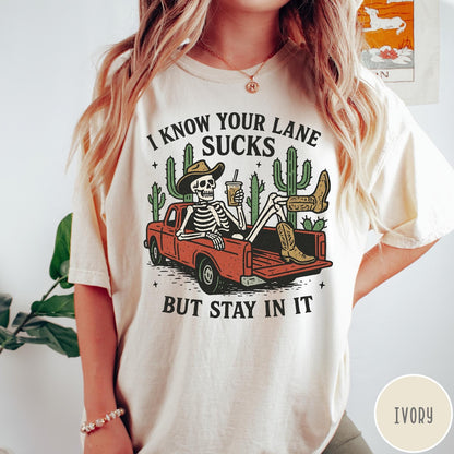 Comfort Colors tee in Ivory featuring western skeleton graphic with cowboy hat and boots in pickup truck