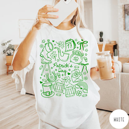Comfort Colors tee in White featuring line art style St. Patrick's Day icons including shamrocks and leprechaun hat