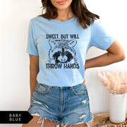 Comfort Colors tee in Baby Blue featuring graphic style raccoon illustration with text Sweet, but will throw hands