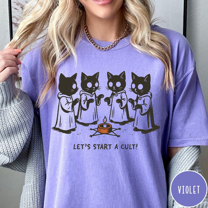 Comfort Colors tee in Violet featuring illustrated style graphic of four cats in robes around a candle