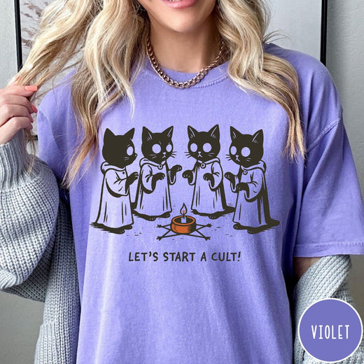 Comfort Colors tee in Violet featuring illustrated style graphic of four cats in robes around a candle