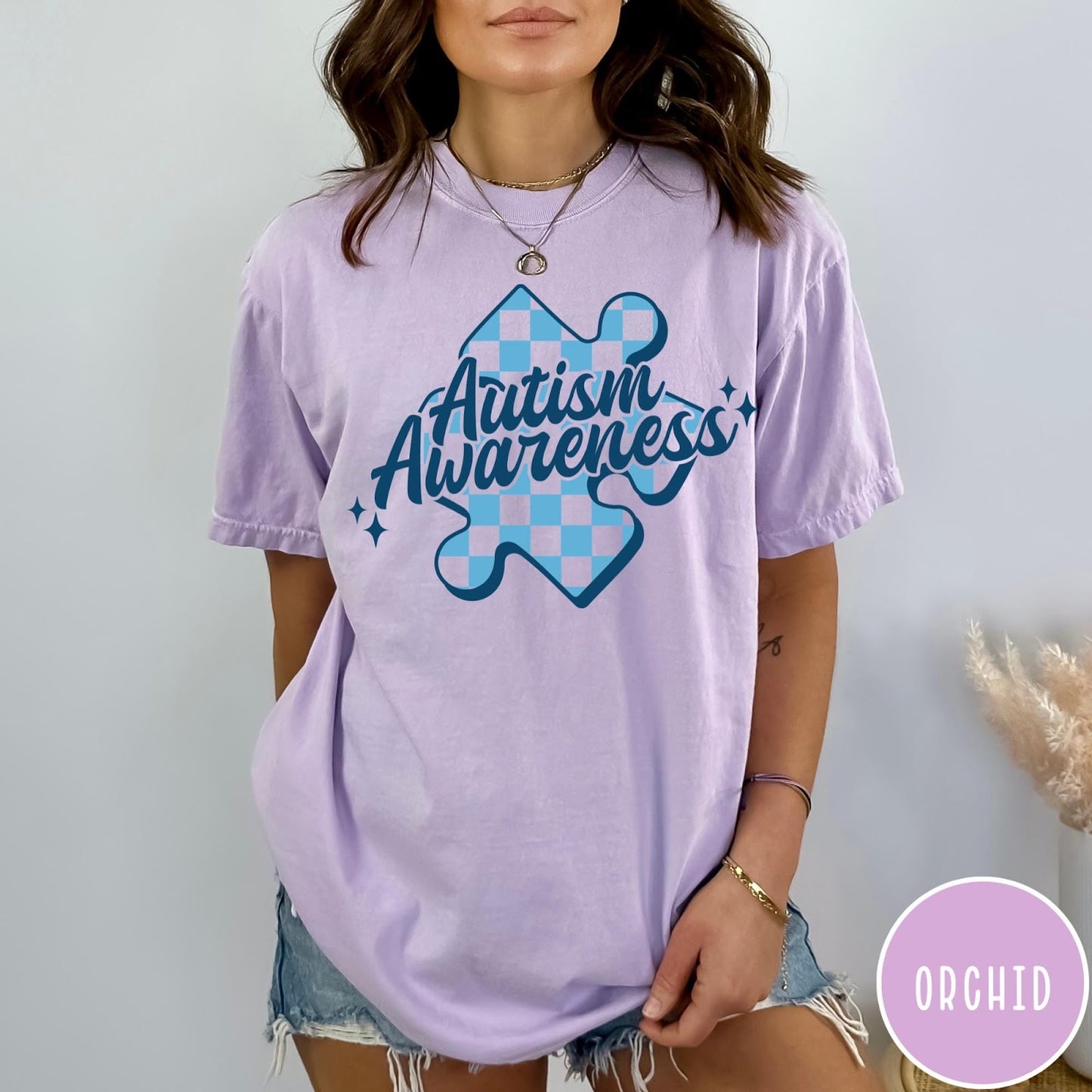 Comfort Colors tee in Orchid featuring casual style with a blue checkered puzzle piece Autism Awareness graphic