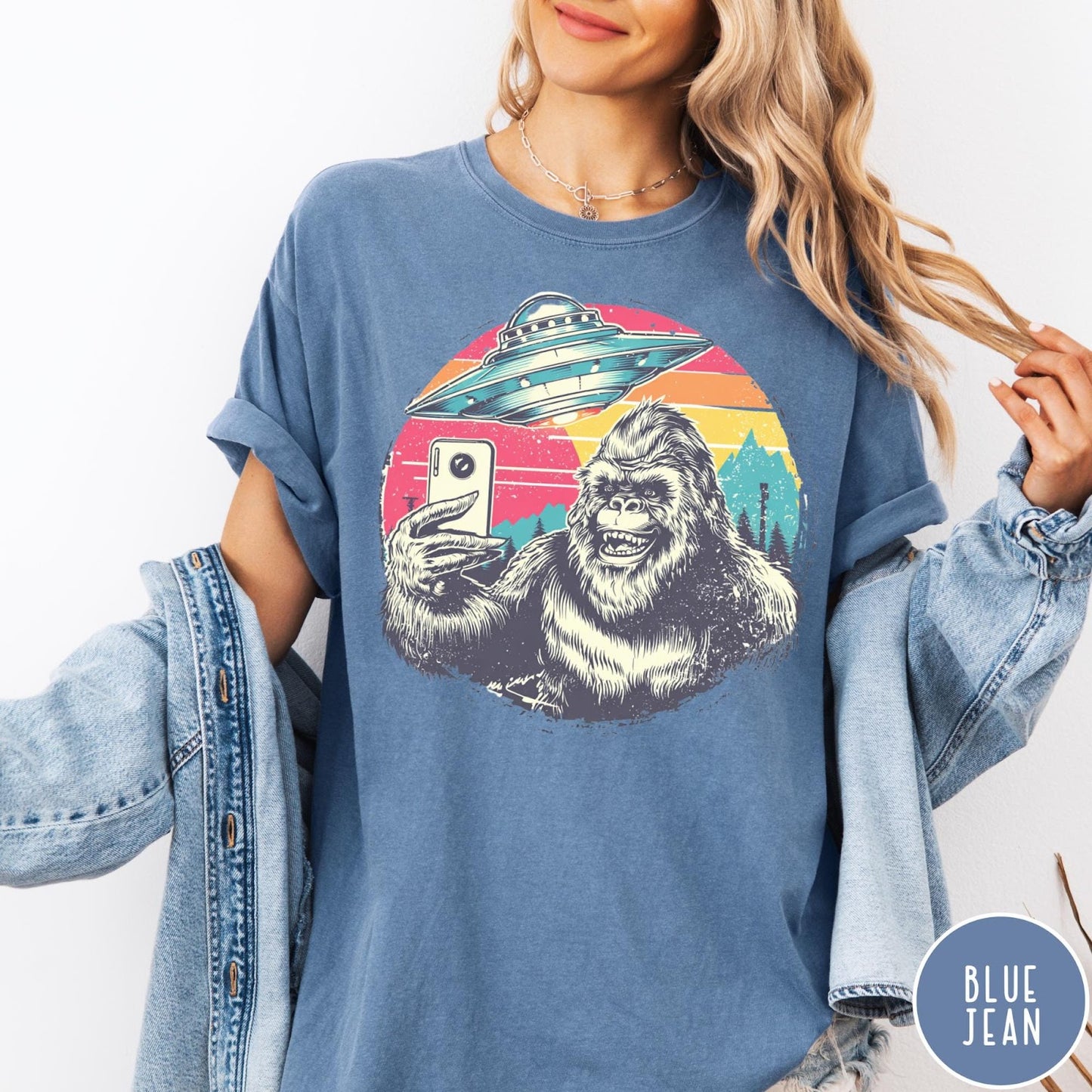 Comfort Colors tee in Blue Jean featuring retro graphic design of Bigfoot taking a selfie with a UFO