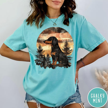 Comfort Colors tee in Chalky Mint featuring vintage style graphic of a dachshund sitting in a forest sunset