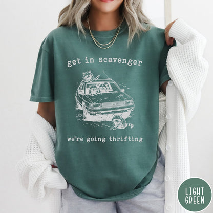 Comfort Colors tee in Light Green featuring illustrated style graphic of raccoons riding in a car and thrifting