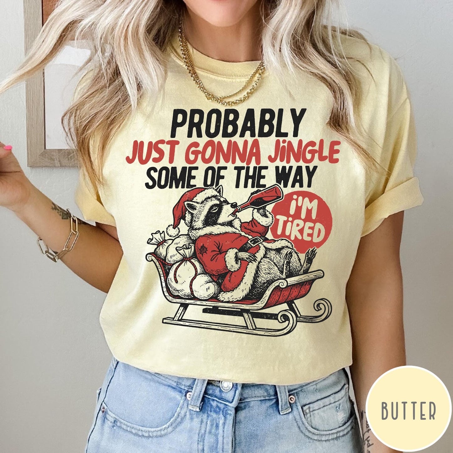 Comfort Colors tee in Butter featuring festive raccoon graphic in a sleigh with holiday text design