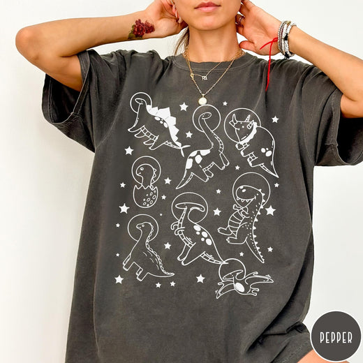 Comfort Colors tee in Pepper featuring line art graphic of various dinosaurs wearing astronaut helmets in space