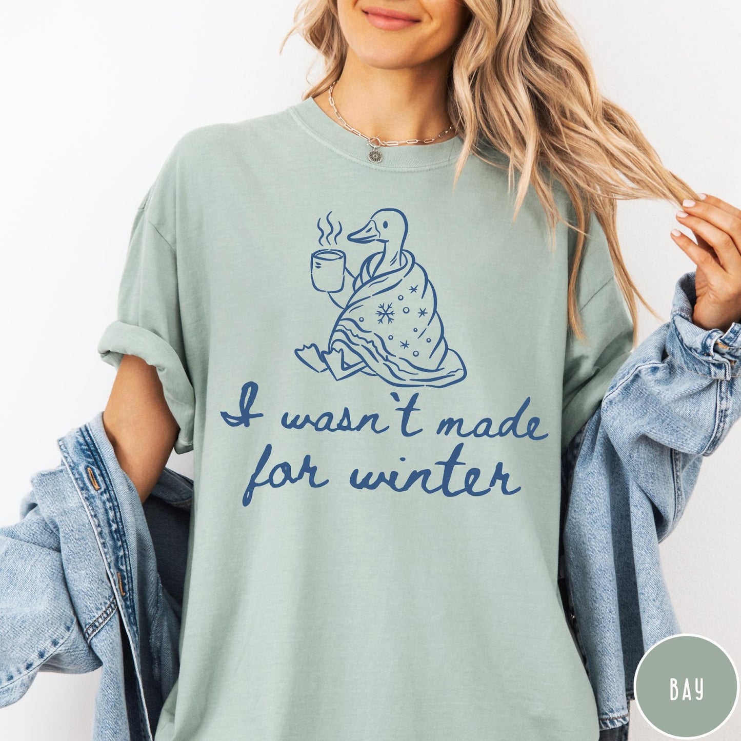 Comfort Colors tee in Bay featuring line art graphic of a duck wrapped in a blanket drinking coffee