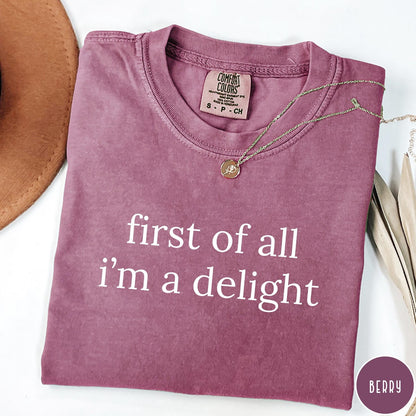 Comfort Colors tee in Berry featuring typography design with the text first of all i'm a delight