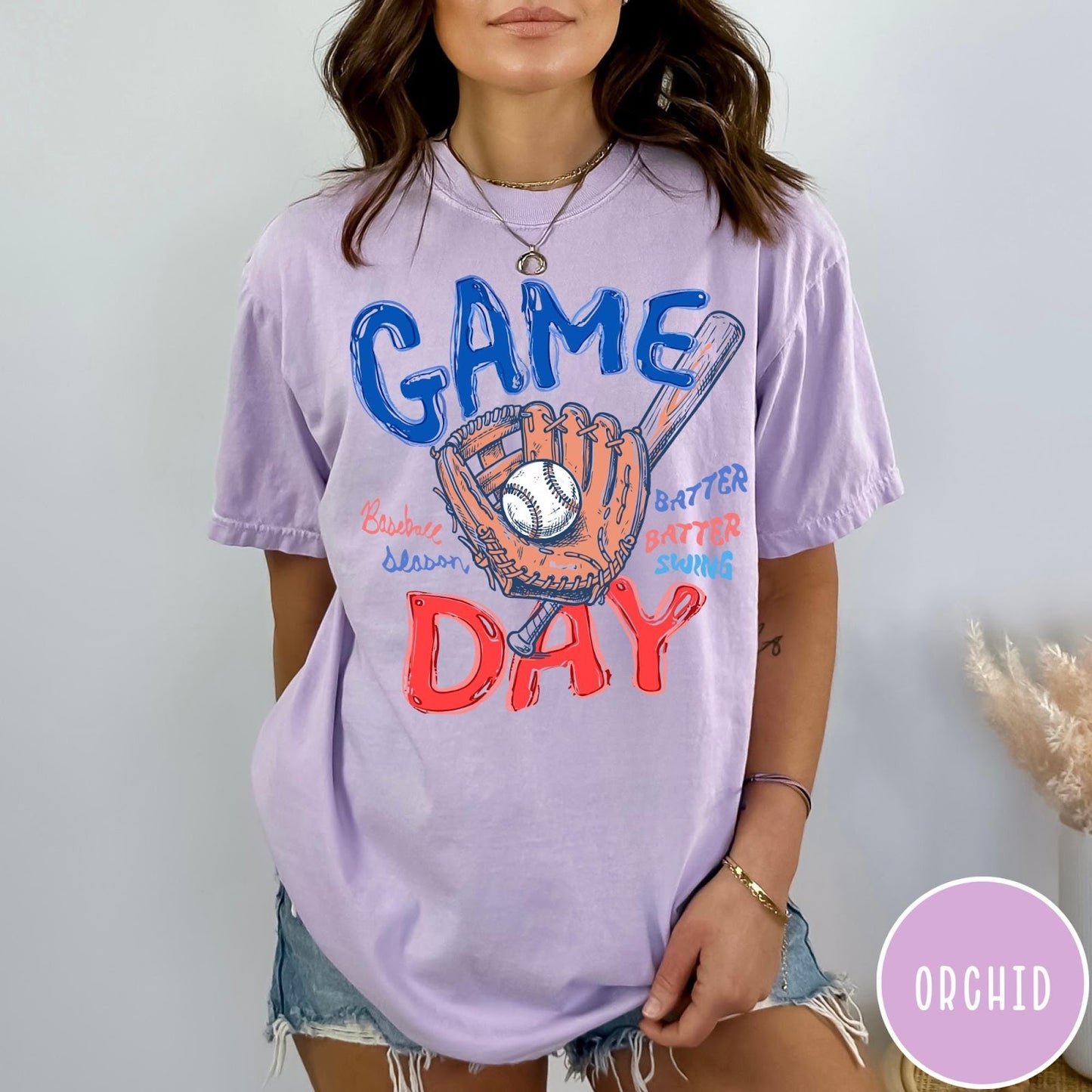 Comfort Colors tee in Orchid featuring baseball design with glove, ball, bat, and Game Day text graphic