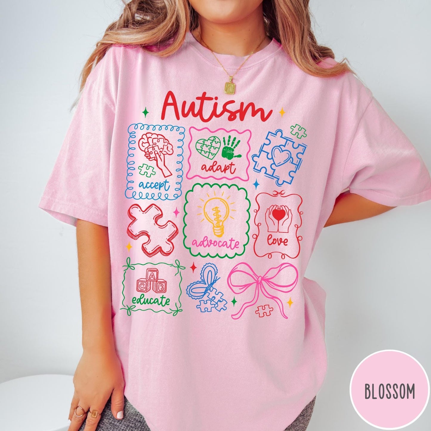 Comfort Colors tee in Blossom featuring coquette style autism awareness graphic with puzzle pieces and colorful icons