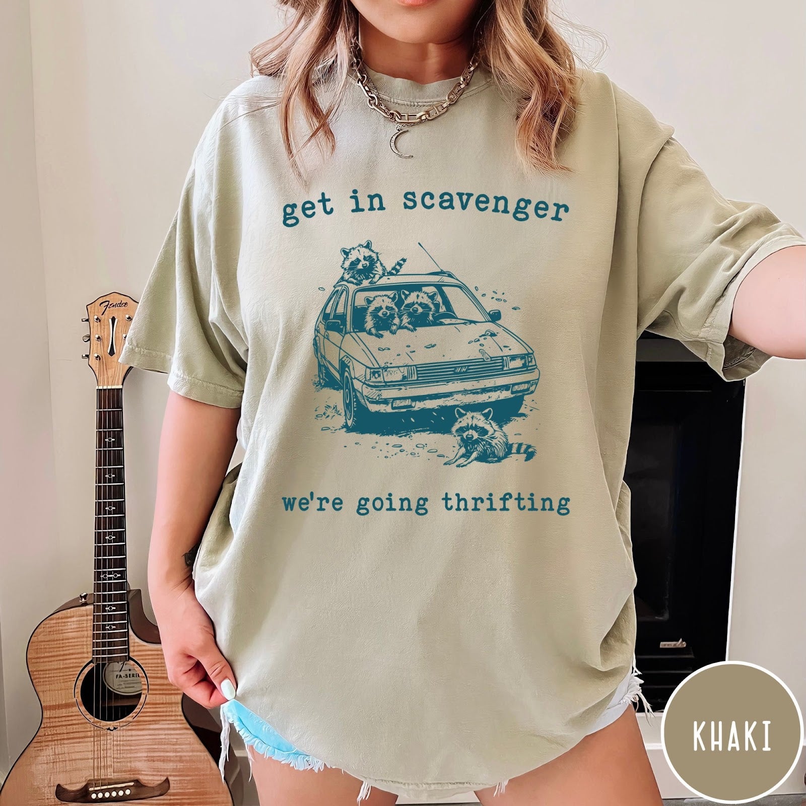 Comfort Colors tee in Khaki featuring illustrated style graphic of raccoons riding in a car and thrifting