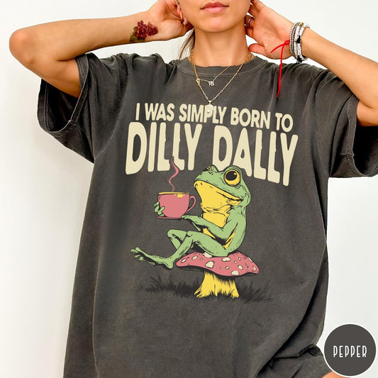 Comfort Colors tee in Pepper featuring illustrative style graphic of a frog sitting on a mushroom drinking tea