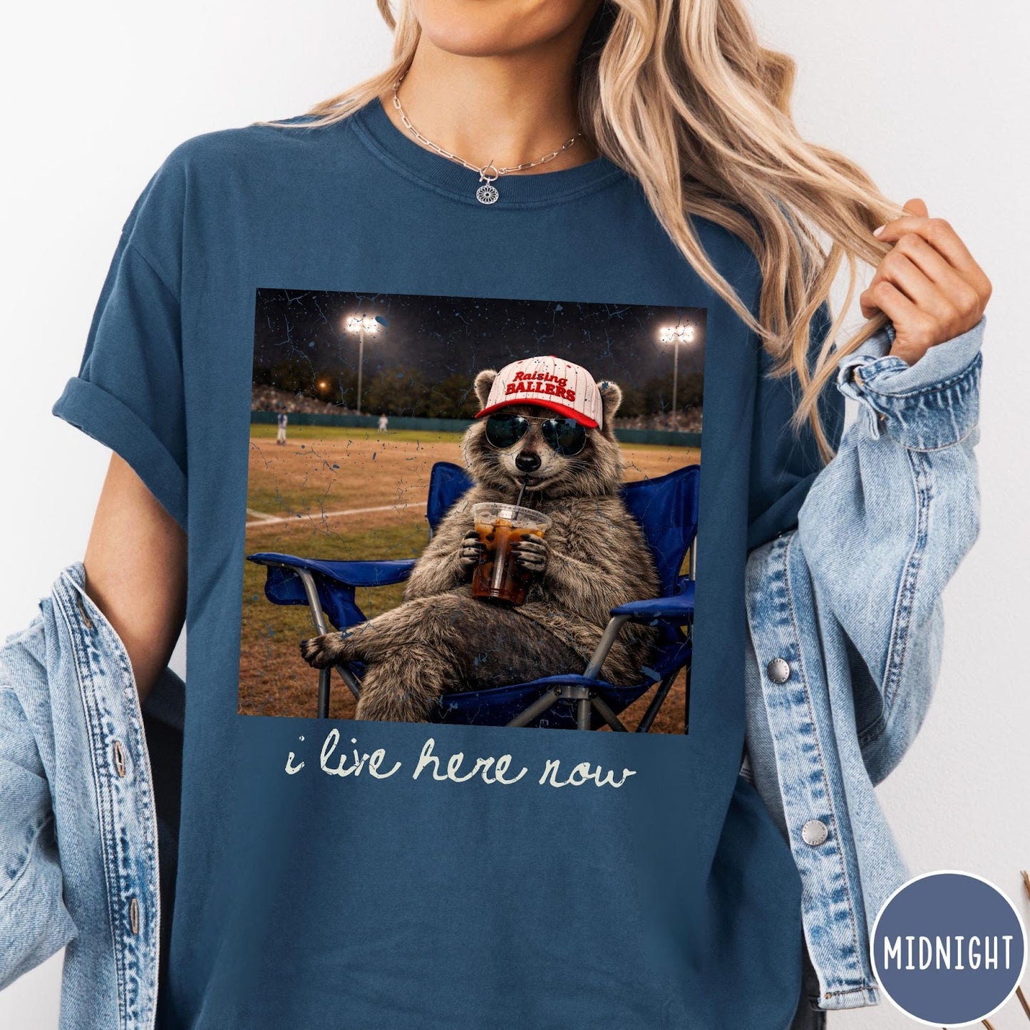 Comfort Colors tee in Midnight featuring graphic raccoon wearing sunglasses and baseball cap sitting in camping chair