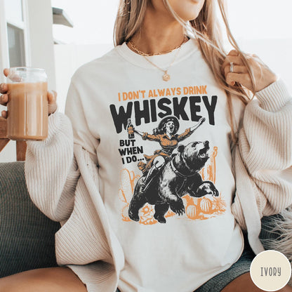 Comfort Colors tee in Ivory featuring vintage style graphic of a woman riding a bear holding whiskey
