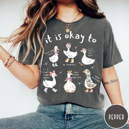 Comfort Colors tee in Pepper featuring whimsical graphic style with six cute geese and motivational text phrases