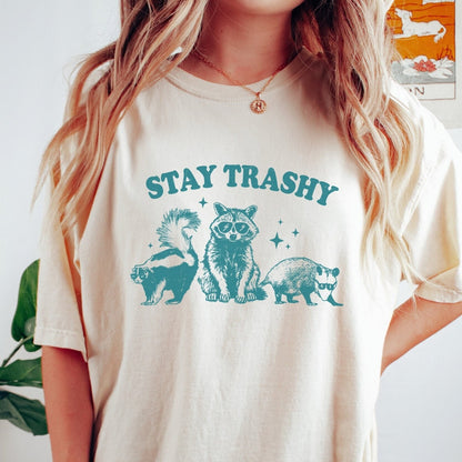 Comfort Colors tee in Ivory featuring graphic style raccoon, skunk, and opossum wearing sunglasses with Stay Trashy text