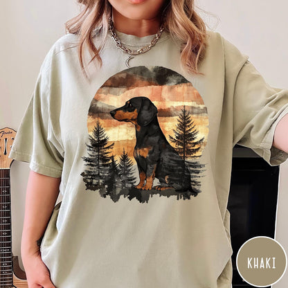 Comfort Colors tee in Khaki featuring vintage style dachshund dog graphic with forest and sunset background